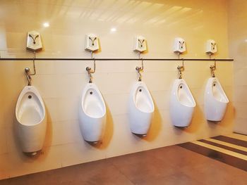 White urinals mounted on yellow wall in public restroom