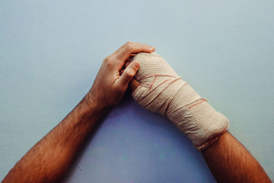 Cropped hand of man wrapped in bandage on table