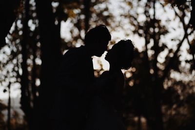 Side view of couple standing against trees