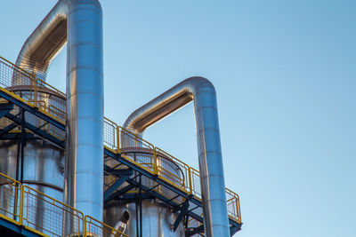 Low angle view of industry against clear blue sky