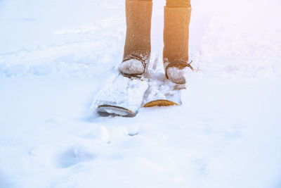 Low section of woman standing on snow covered field