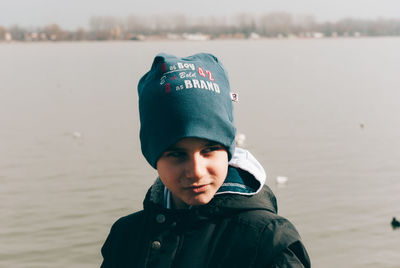 Close-up of boy in knit hat against lake