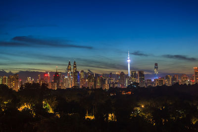 Illuminated buildings in city against sky at night