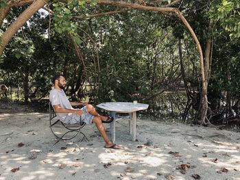 People sitting on seat against trees