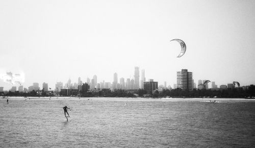 Scenic view of sea by cityscape against sky