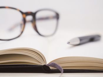 Close-up of eyeglasses and pen on open book
