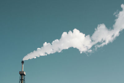 Low angle view of smoke emitting from chimney against clear blue sky