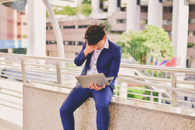 Stressed businessman using laptop in city