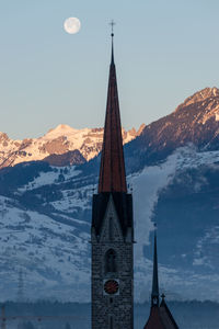 Schaan, liechtenstein, january 19, 2022 full moon in the morning behind a tower of a catholic church 