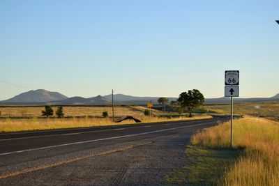 Road passing through landscape against clear blue sky