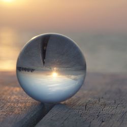 Close-up of crystal ball on table against sky during sunset