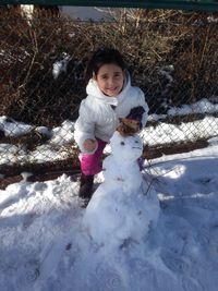 Portrait of cute girl making snowman during winter