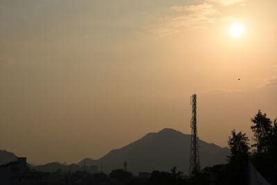 Silhouette trees and buildings against sky during sunset