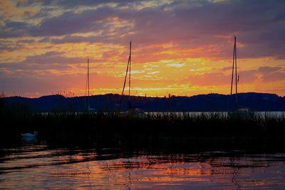 Scenic view of lake against cloudy sky during sunset