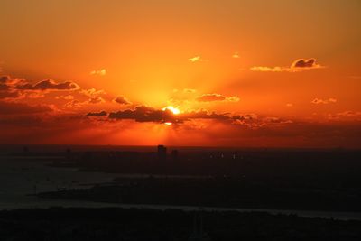 Silhouette landscape against orange sky during sunset