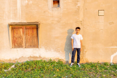 Full length of young man standing against building