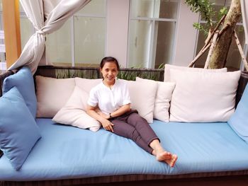 Portrait of smiling woman sitting on sofa at home