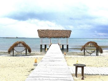 Deck chairs by sea against sky