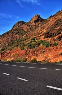 Road by mountain against sky