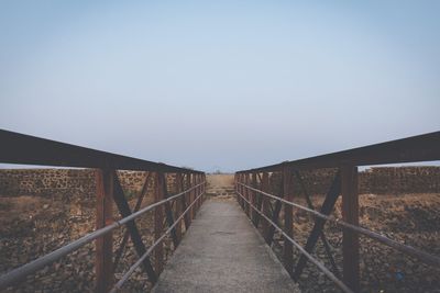 Footbridge over land against clear sky