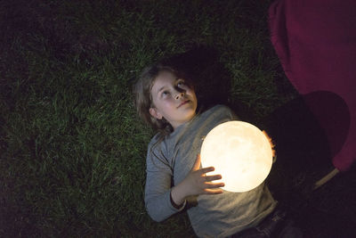 Girl lying on meadow, holding moon