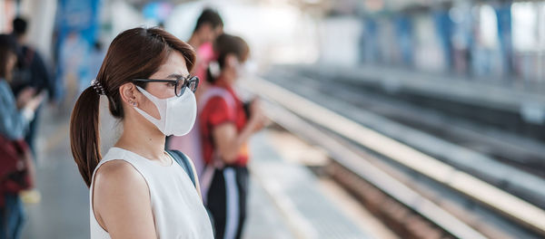 Side view of woman wearing flu mask standing outdoors