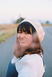 Portrait of smiling young woman against road