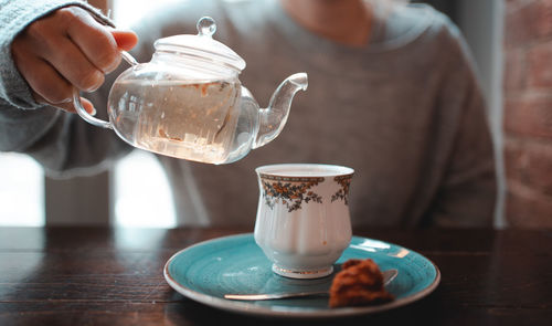 Midsection of woman holding coffee cup on table