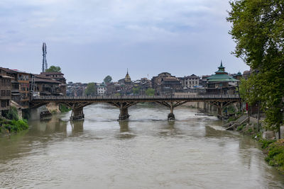 Arch bridge over river against cloudy sky