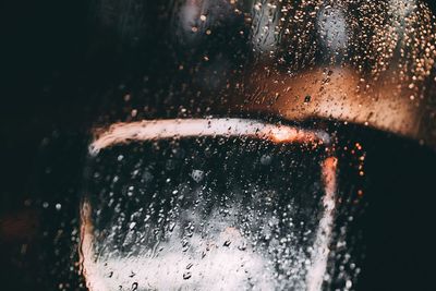 Close-up of wet glass against sky