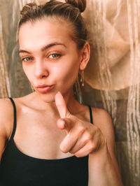 Young woman gesturing while standing against curtain