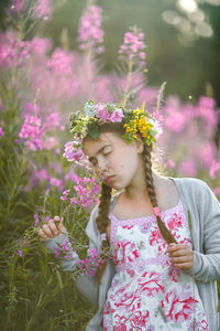 Girl smelling flowers while standing at filed