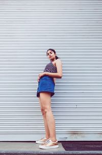 Portrait of young woman standing against wall