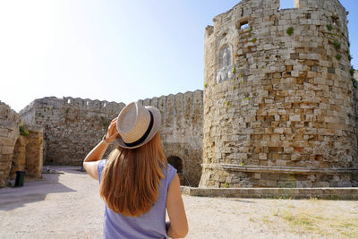 Back view of traveler girl visiting rhodes fortifications. young tourist visiting southern europe.