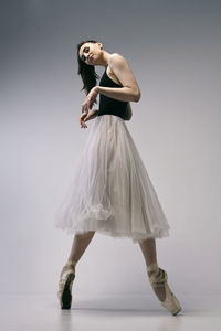 A ballerina in a bodysuit improvises classical and modern choreography in a photo studio