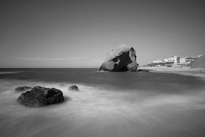 Rock formation in sea against clear sky