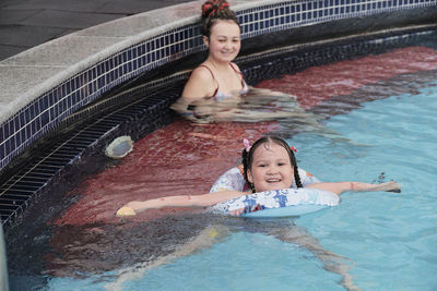 Happy cute asian little girl swimming in rubber ring, having fun in open air thermal pool.