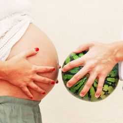 Close-up of pregnant belly and watermelon