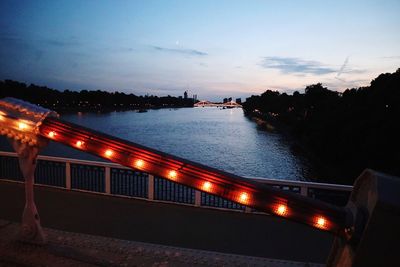 Illuminated bridge over river against sky at night