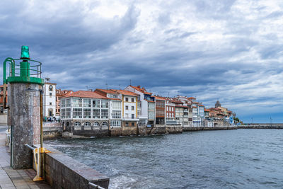 Buildings by sea against sky