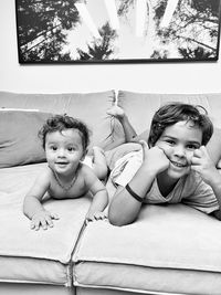 Portrait of siblings sitting on sofa at home