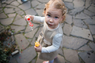 Portrait of cute girl holding bubble wand on footpath