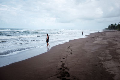 Scenic view of two people walking on beach