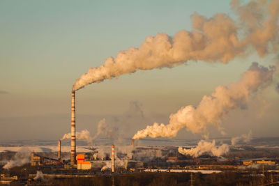 Smoke emitting from factory against sky