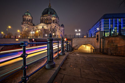 Light trails in canal by berlin cathedral against sky at night