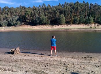 Rear view of man standing on riverbank