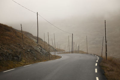 Empty road by mountain against sky