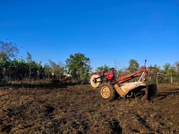 Tractor on field against clear blue sky