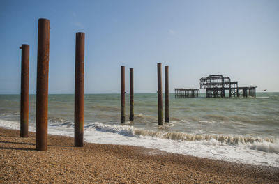 Wooden jetty on calm beach against clear sky