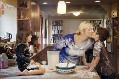 Daughter looking at mother kissing son